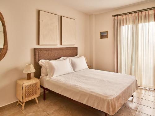 a bedroom with a bed with white sheets and a window at Apartamentos Turísticos Casa de La Borrega in Estepona