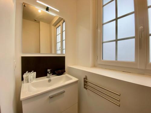 une salle de bain blanche avec un lavabo et un miroir dans l'établissement Henry II - Petit appartement lumineux - 013, à Rouen