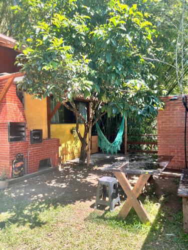 a tree with a hammock in front of a house at Chalé Cabana Lumiar in Nova Friburgo