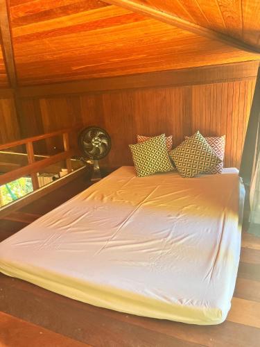 a bed in a room with a wooden wall at Chalé Cabana Lumiar in Nova Friburgo