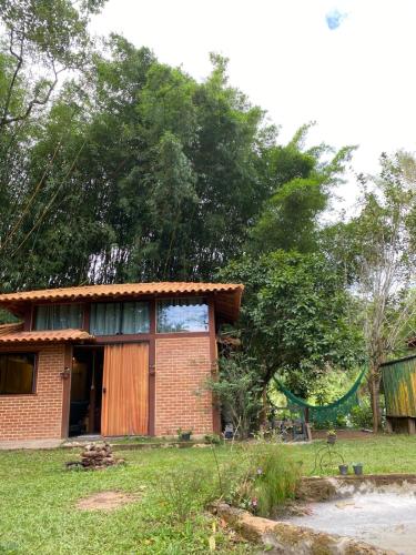 a house with a hammock in front of it at Chalé Cabana Lumiar in Nova Friburgo
