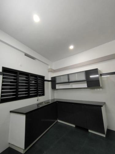 a kitchen with black cabinets and a white wall at Achandy Arcade in Kakkadampoyil
