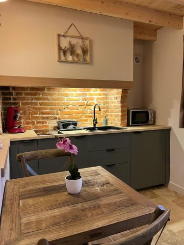 a kitchen with a wooden table with a flower on it at Le Cocon in Le Breuil-en-Auge