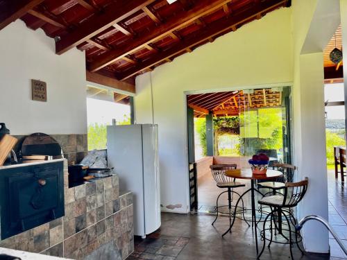 Una cocina con mesa y sillas y un refrigerador. en Rancho Green22Home, en Ibiraci