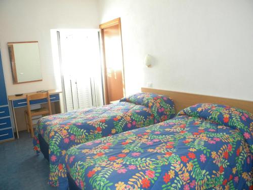イスキアにあるアルベルゴ ロカンダ スル マーレのベッド2台と鏡が備わるホテルルームです。