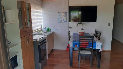 ピチダンギにあるPichidangui, Las Rosas casa 4 personasのキッチン(テーブル付)、壁掛けテレビが備わります。