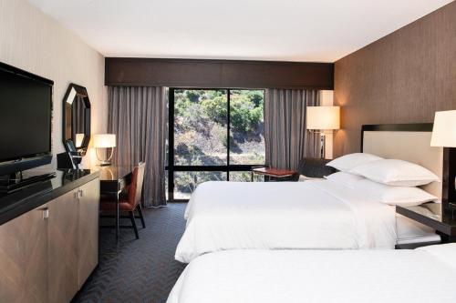 a hotel room with two beds and a flat screen tv at Sheraton Mission Valley San Diego Hotel in San Diego