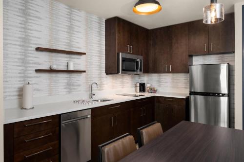a kitchen with wooden cabinets and a stainless steel refrigerator at Residence Inn by Marriott East Peoria in Peoria