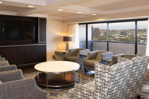 a hotel room with chairs and a tv and a table at Sheraton Mission Valley San Diego Hotel in San Diego