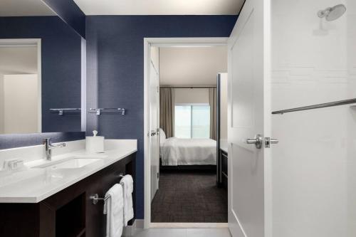 a bathroom with a sink and a shower with a bed at Residence Inn by Marriott East Peoria in Peoria