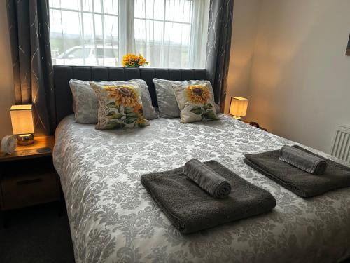 a bed with two towels on it with a window at High Oak Holiday Cottage in Thirsk