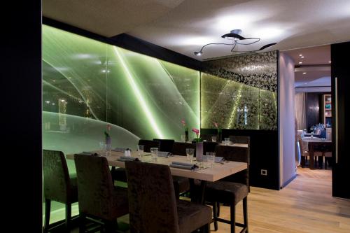 a dining room with a table with chairs and a green wall at Atrium Hotel Mainz in Mainz