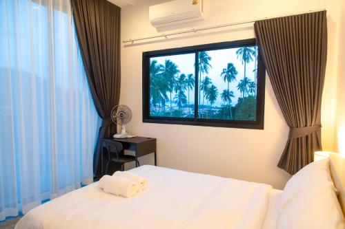 a bedroom with a bed and a window with palm trees at Scenic Lamai Getaway in Amphoe Koh Samui