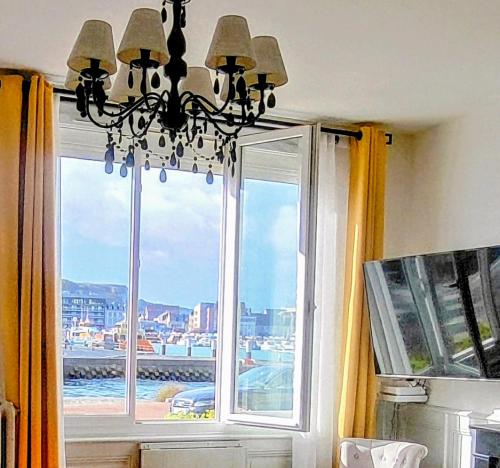 a chandelier in a room with a large window at LE WELCOME vue port appartement plain pied in Fécamp