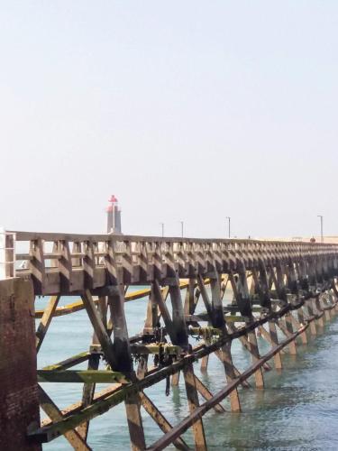 a pier with a lighthouse in the water at LE WELCOME vue port appartement plain pied in Fécamp