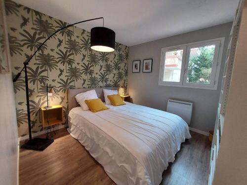 une chambre avec un lit avec des draps blancs et des oreillers jaunes dans l'établissement Résidence ERMITAGE. Appartement pour 4 personnes au centre-ville d'Hossegor. Wifi gratuit, à Soorts-Hossegor