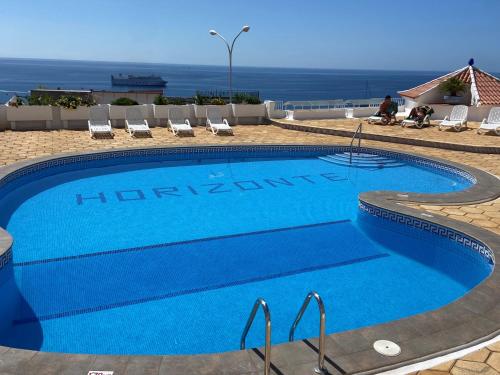 una gran piscina azul con sillas y el océano en Horizonte 22 Sea view relax in luxury, en Los Cristianos