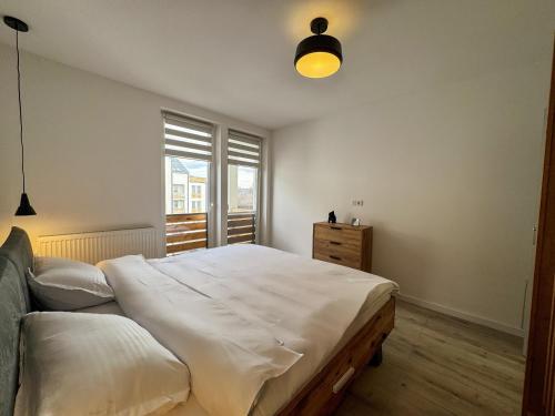 ein Schlafzimmer mit einem großen weißen Bett und einem Fenster in der Unterkunft Rhapsody Home - Urban quiet area with Parking&King Bed&Balcony in Târgu Mureș