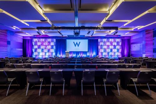 a room with tables and chairs and a screen at W Scottsdale in Scottsdale