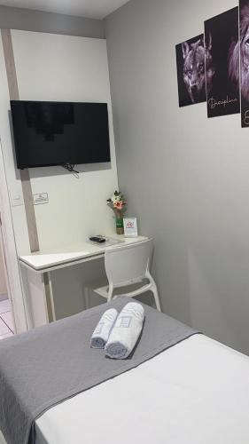 a bedroom with a bed and a desk with a television at Hotel Estação in Barueri