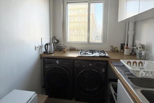 Il comprend une cuisine équipée d'une cuisinière. four supérieur à côté d'une fenêtre dans l'établissement Grand appartement cosy au calme, à Montrouge