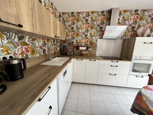 La Petite Sablaise في سانت جيل كروا دي فيي: مطبخ بدولاب بيضاء وورق ورق جدران