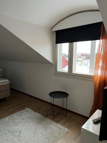 a living room with a window and a stool at Apartment Klemetti in Vaasa