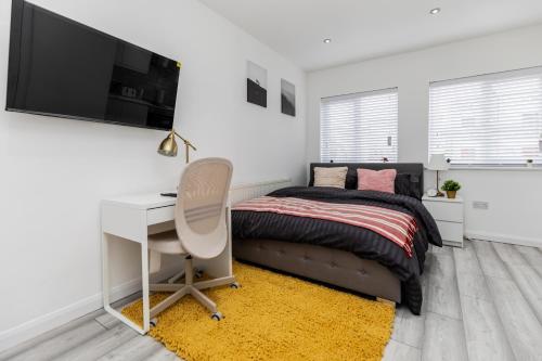 a bedroom with a bed and a desk and a tv at Deluxe studio Apartments - City Airport & Excel Ideal for Long stay in London