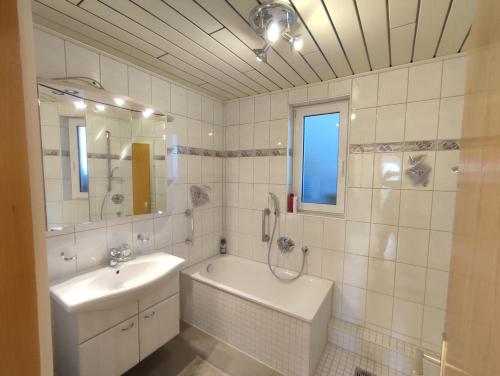 a white bathroom with a sink and a tub and a sink at Kaiserberg-Apartments "Nahe dem Hohenstaufen" in Wangen