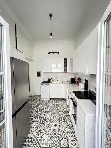 une cuisine avec des armoires blanches et un sol carrelé dans l'établissement Un rez de jardin en plein centre, à Cannes