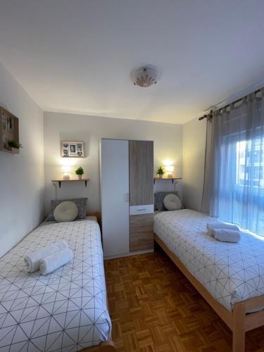 two twin beds in a room with a window at Apartman Neva ,prostrani stan u blizini mora in Pula
