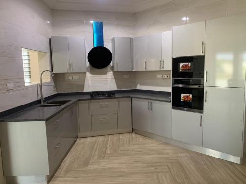 a large kitchen with white cabinets and a blue light at Bonvilla in Accra