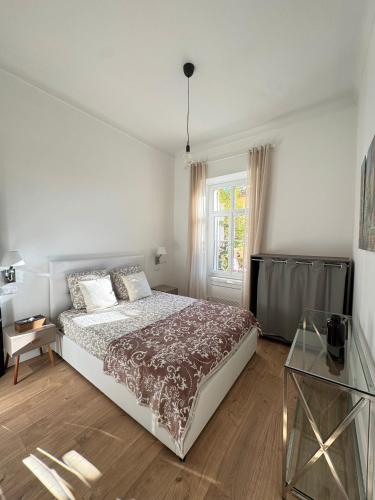 une chambre blanche avec un lit et une fenêtre dans l'établissement Un rez de jardin en plein centre, à Cannes