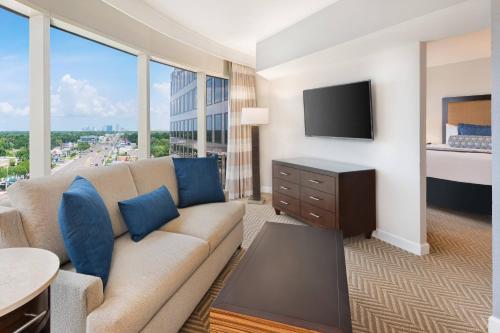 a living room with a couch and a flat screen tv at The Westshore Grand, A Tribute Portfolio Hotel, Tampa in Tampa