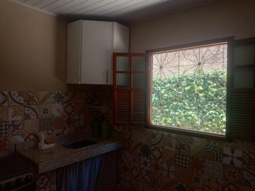 a kitchen with a window in the corner of a room at Casa Centro pertinho da praia in Piúma