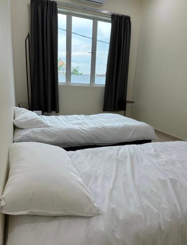 two white beds in a room with a window at May Homestay in Port Dickson