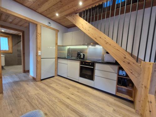 une cuisine avec des placards blancs et un escalier en bois dans l'établissement Le Petit Chalet Villaret - App 6 pers - proche La Rosière, à Montvalezan