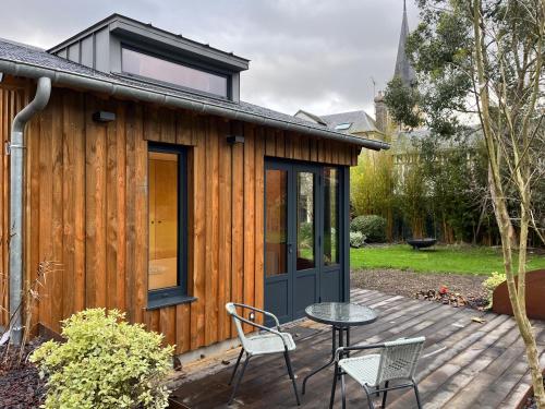 a small house with a table and chairs on a deck at Le Cocon in Le Breuil-en-Auge