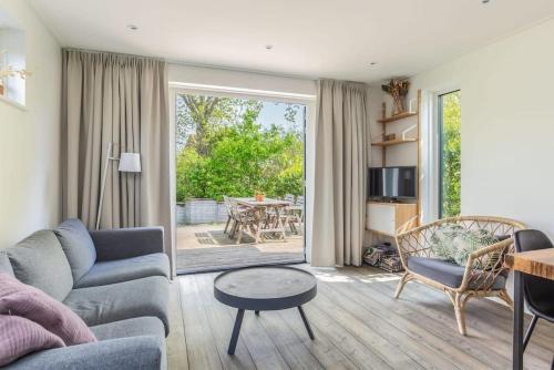 een woonkamer met een bank en een tafel bij Hello Zeeland - Vakantiehuis Duinenburg 22A in Domburg