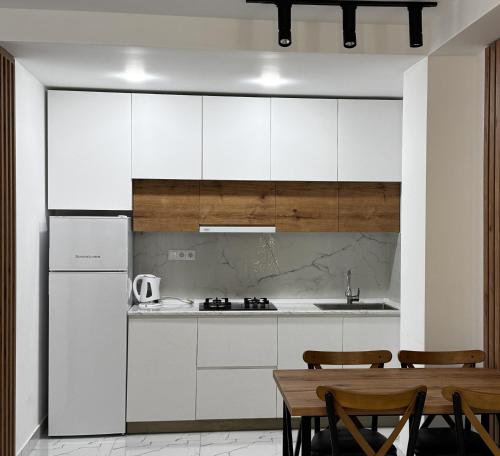 una cucina con mobili bianchi, tavolo e sedie di White Bridge Riverside a Kutaisi