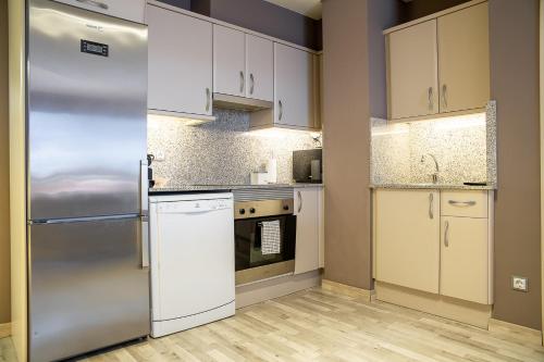 a kitchen with white cabinets and a stainless steel refrigerator at Terraza Privada I Refugio Tranquilo con Vistas in Canillo