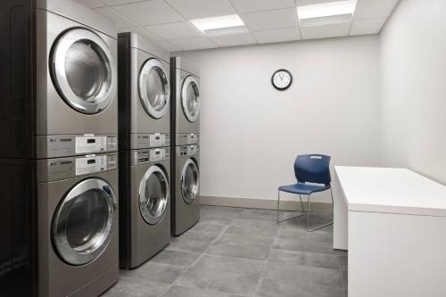 a laundry room with four washing machines and a blue chair at TownePlace Suites by Marriott Tampa Casino Area in Tampa
