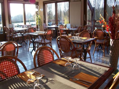 a dining room with tables and chairs and windows at L'Aquarelle - Camping in La Souterraine