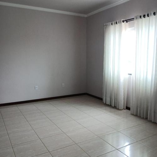 an empty room with white curtains and a tile floor at Queiroz e Melânia in Penha