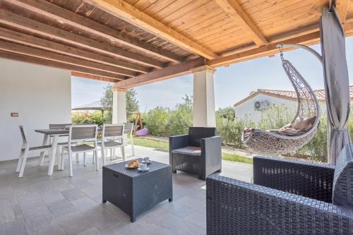 a patio with a table and chairs and a hammock at Villino Elisa in Tertenìa