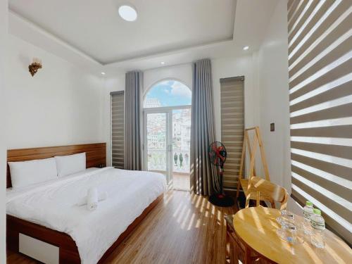 a bedroom with a bed and a table and a window at Mai House Da Lat in Xuan An