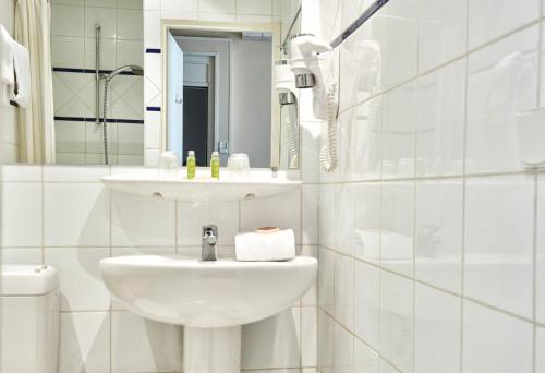 a white bathroom with a sink and a toilet at Hôtel du Nord in Annecy