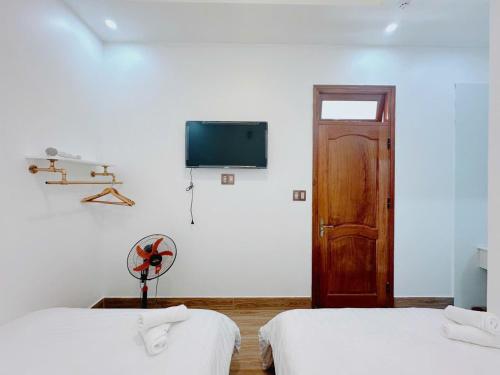 a room with two beds and a tv on the wall at Mai House Da Lat in Xuan An