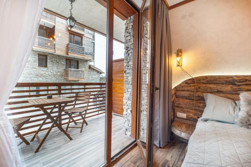 een slaapkamer met een bed en een tafel op een balkon bij Host2U Authentic Bansko Apartment - Free Parking in Bansko