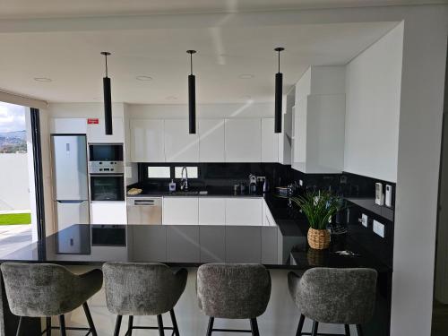 a kitchen with black and white cabinets and bar chairs at Bela Vista Funchal Villa in Funchal